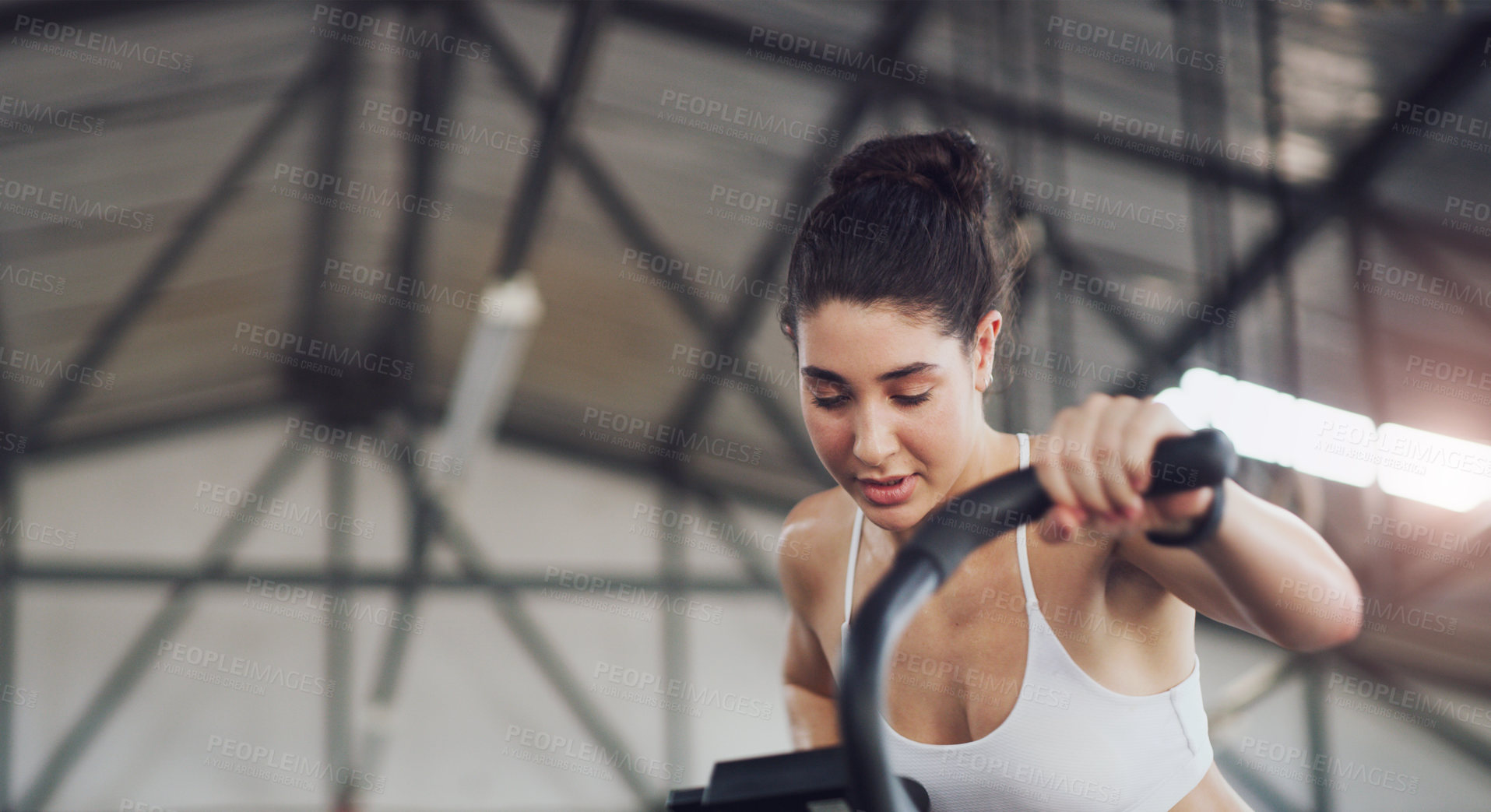 Buy stock photo Shot of a young woman working out on an exercise bike in a gym