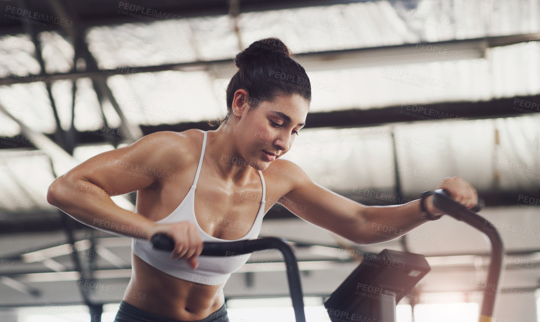 Buy stock photo Shot of a young woman working out on an exercise bike in a gym