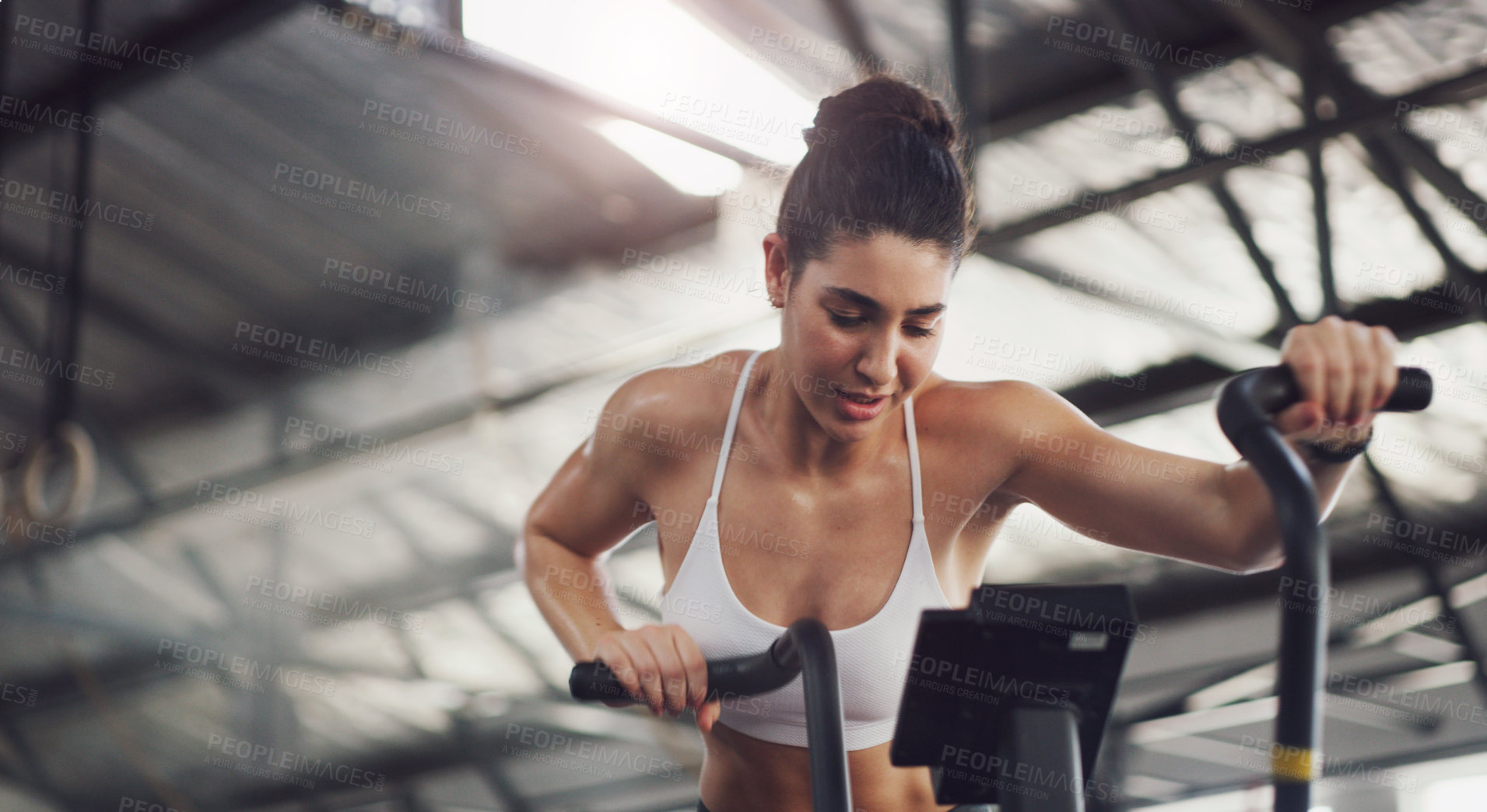 Buy stock photo Shot of a young woman working out on an exercise bike in a gym