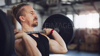 Buy stock photo Shot of a young man exercising with a barbell in a gym
