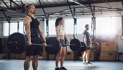 Buy stock photo Shot of a group of people exercising together with barbells in a gym