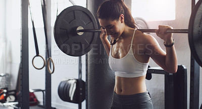 Buy stock photo Shot of a young woman exercising with a barbell in a gym