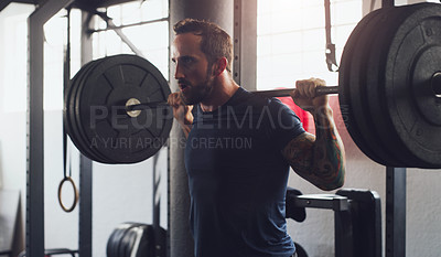 Buy stock photo Shot of a young man exercising with a barbell in a gym