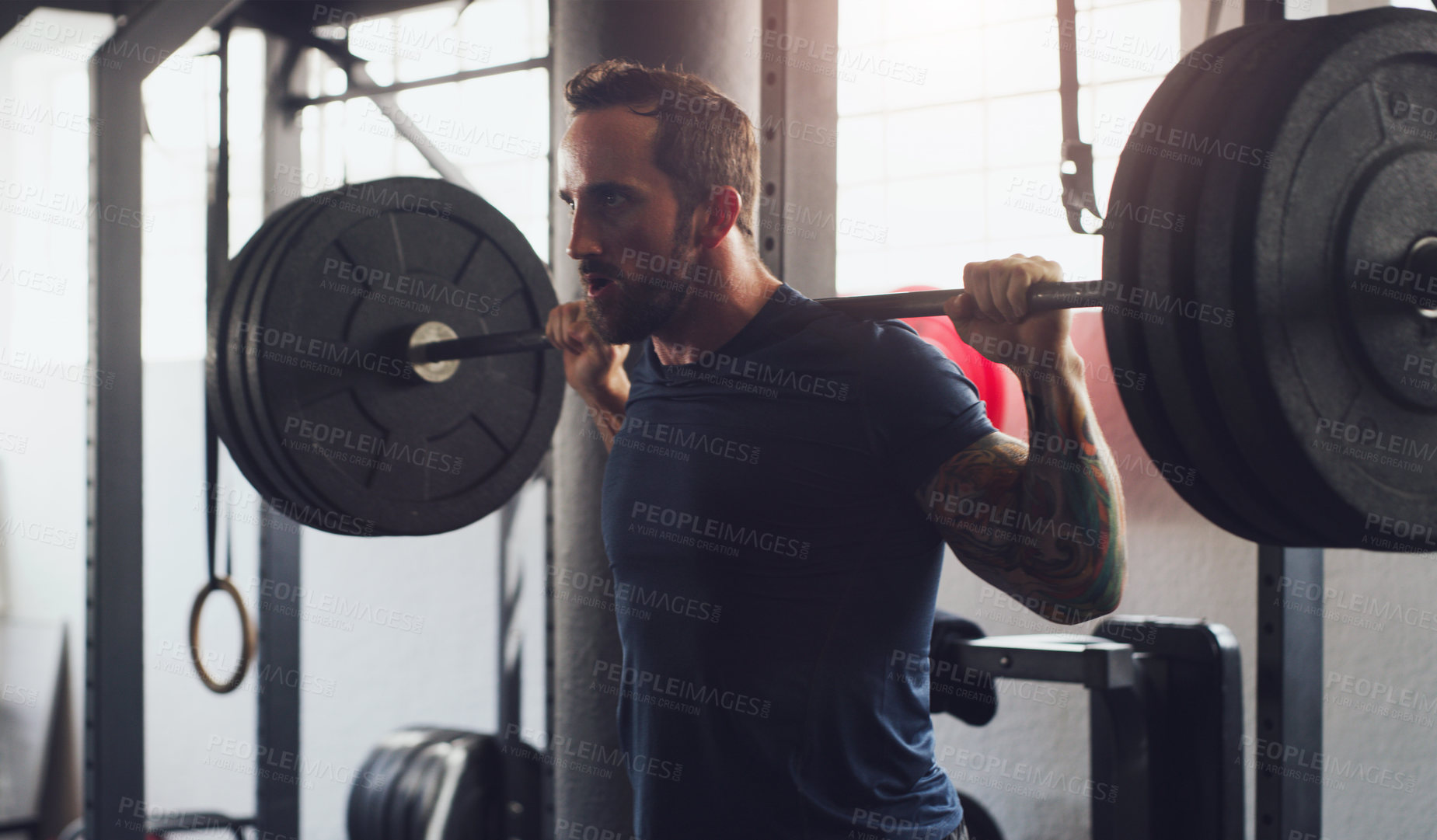 Buy stock photo Shot of a young man exercising with a barbell in a gym