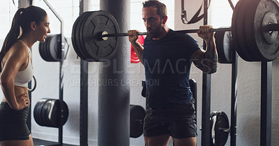 Buy stock photo Shot of a man exercising with a barbell with the help of a trainer in a gym