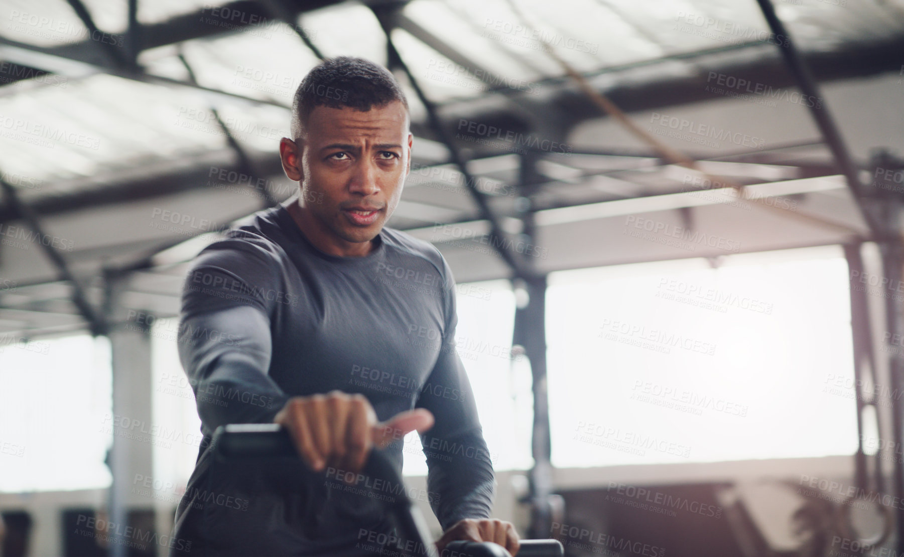 Buy stock photo Shot of a young man working out on an exercise bike in a gym