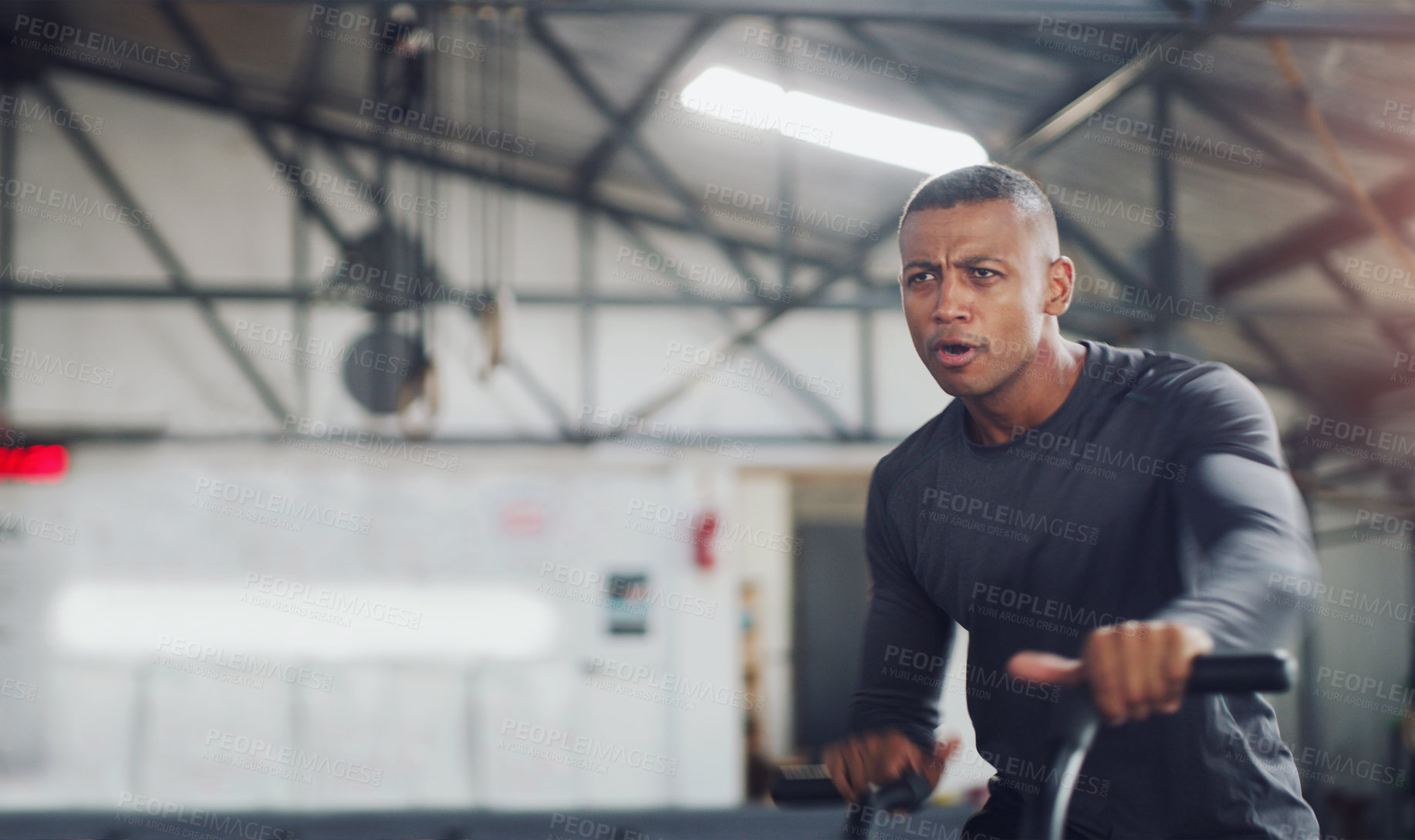 Buy stock photo Shot of a young man working out on an exercise bike in a gym