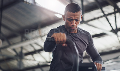 Buy stock photo Shot of a young man working out on an exercise bike in a gym