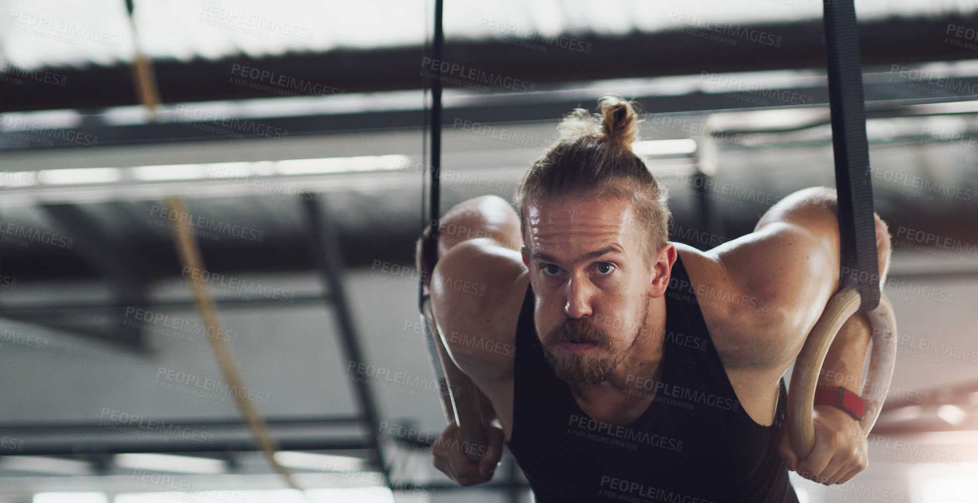 Buy stock photo Shot of a young man exercising with gymnastic rings in a gym