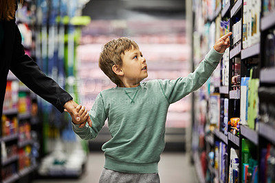 Buy stock photo Shot of a little boy take something of a shelf in a supermarket