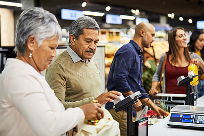 Buy stock photo Shot of a elderly couple paying for their groceries in a supermarket