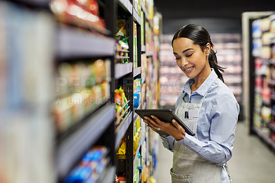 Buy stock photo Shot of a young woman using a tablet at work in a  supermarket