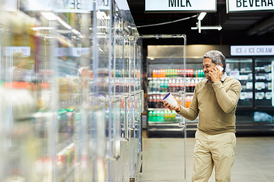 Buy stock photo Shot of a senior man using his phone and shopping for groceries in a supermarket