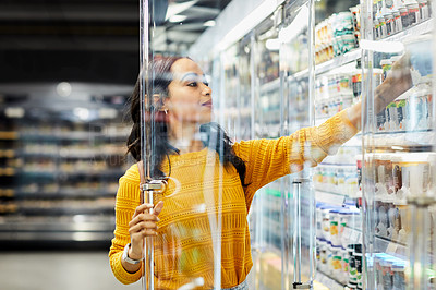 Buy stock photo Shot of a young woman shopping for groceries in a supermarket