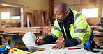 Blueprint, carpentry and laptop with black man in workshop for building checklist or process. Computer, floor plan and paperwork with mature carpenter in woodworking plant for construction or design