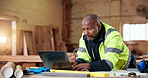 Carpentry, laptop and typing with black man in workshop for checklist or online order. Computer, planning and reading with mature carpenter in woodworking factory for digital agenda or schedule