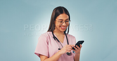 Buy stock photo Happy, woman and nurse with phone in studio with telehealth, communication or texting on mobile app. Smile, mockup space and pediatric healthcare worker with cellphone for research on blue background
