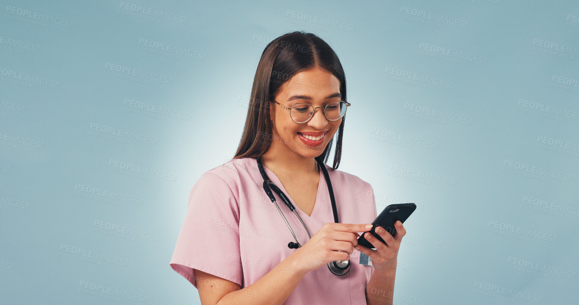 Buy stock photo Happy, woman and nurse with phone in studio with telehealth, communication or texting on mobile app. Smile, mockup space and pediatric healthcare worker with cellphone for research on blue background