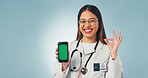 Perfect, green screen and face of doctor with phone in studio for telehealth, medical research or contact. Happy, woman and portrait of healthcare worker with cellphone for app on blue background.