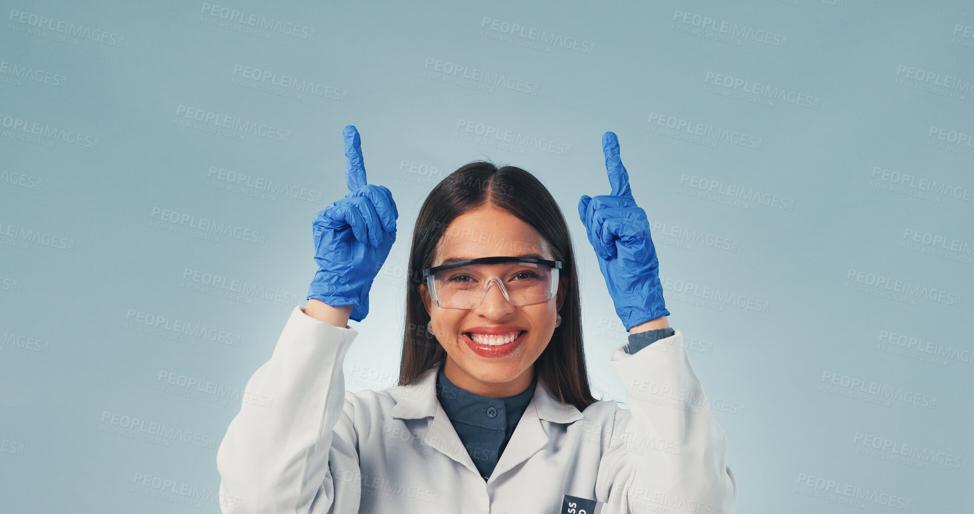 Buy stock photo Pointing, woman and portrait of scientist in studio with mockup space for medical research. Happy, goggles and biologist with presentation of pharmaceutical science project on blue background.