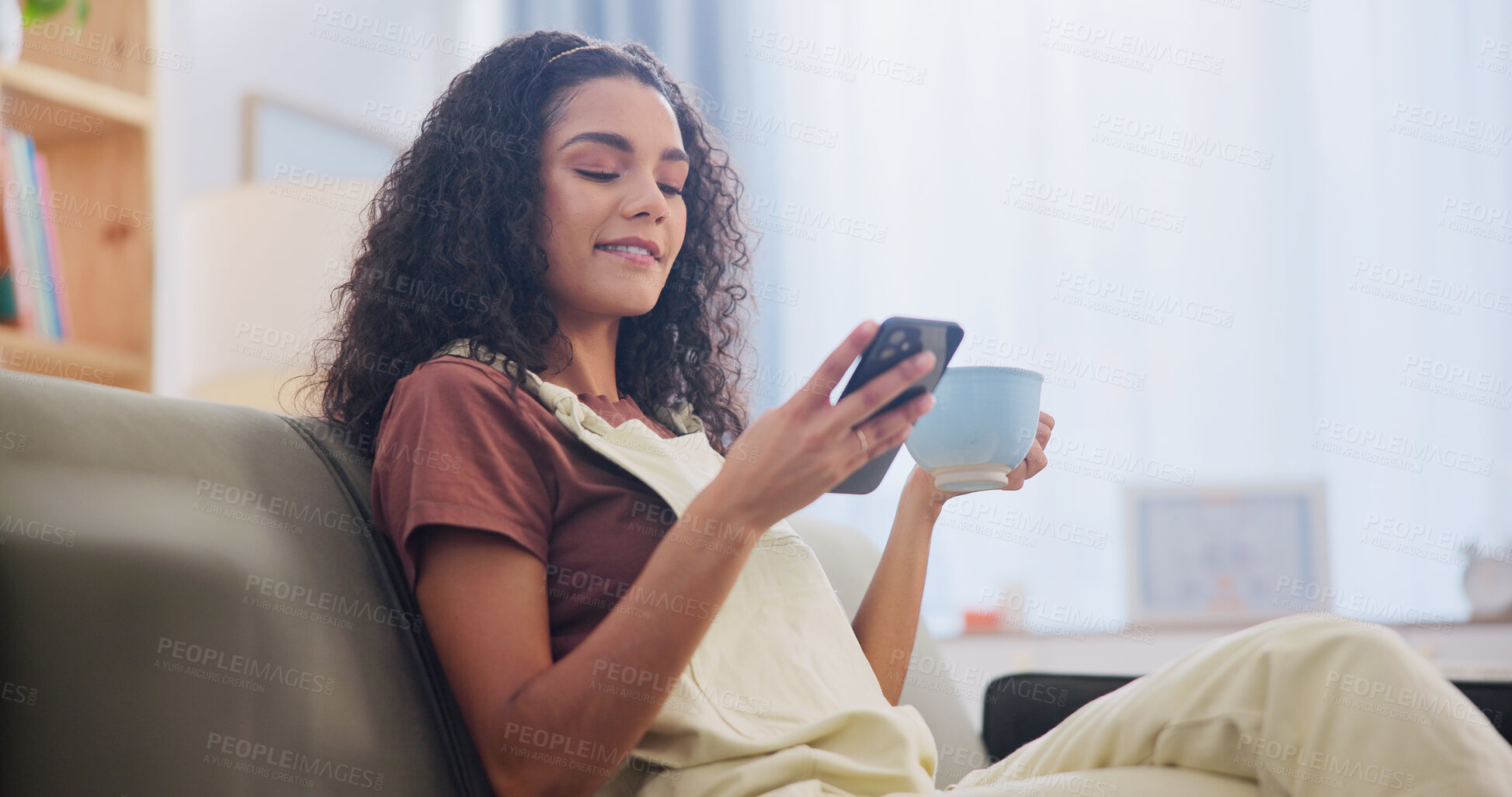 Buy stock photo Cellphone, coffee and woman on sofa in home with texting, social media or networking on mobile app. Smile, relax and person with warm beverage on phone for reading blog on celebrity gossip at house.