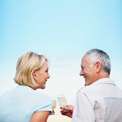 Buy stock photo A cropped rear view shot of a happy mature couple drinking champagne outdoors