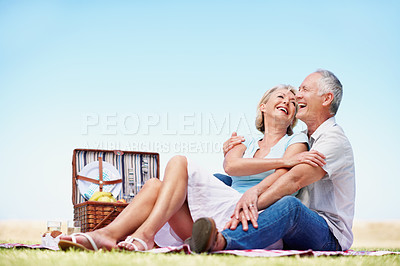 Buy stock photo A mature couple laughing while enjoying a picnic on a sunny day