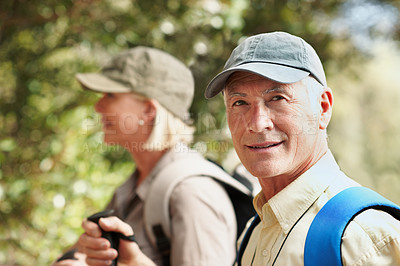 Buy stock photo Portrait of a senior man smiling at the camera while walking in the forest with his wife