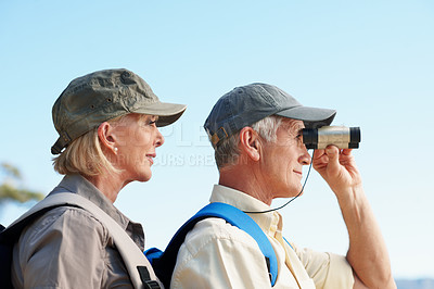 Buy stock photo A cropped shot of a senior man looking through a binocular while standing next to his wife