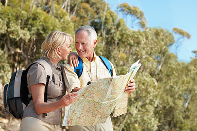 Buy stock photo Shot of a senior couple using a map while standing in a forest
