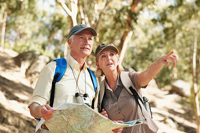 Buy stock photo Shot of a senior couple using a map while standing in a forest
