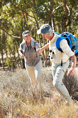 Buy stock photo A shot of a senior man pulling his wife by the hand while walking in the forest
