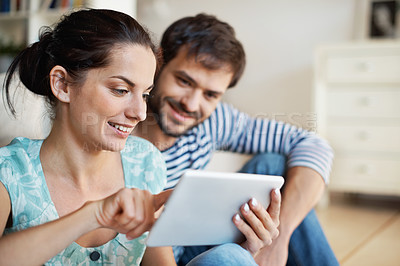 Buy stock photo Shot of a beautiful young couple sitting together with a digital tablet at home