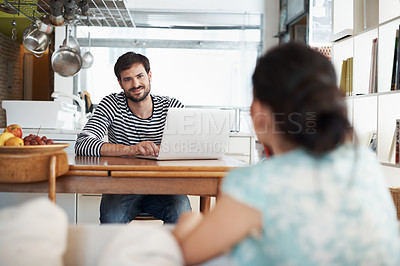 Buy stock photo Shot of a handsome young man sitting with his laptop and looking lovingly at his wife
