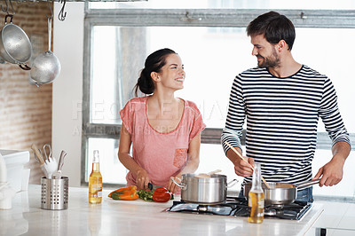 Buy stock photo Shot of a loving young couple cooking together in the kitchen