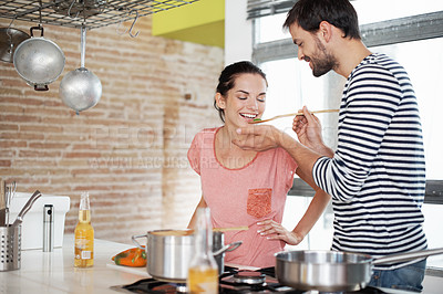 Buy stock photo Shot of a loving young couple cooking together in the kitchen