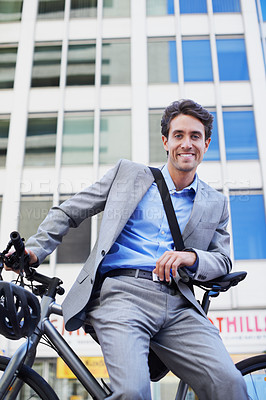 Buy stock photo A handsome businessman sitting on his bicycle in the city central