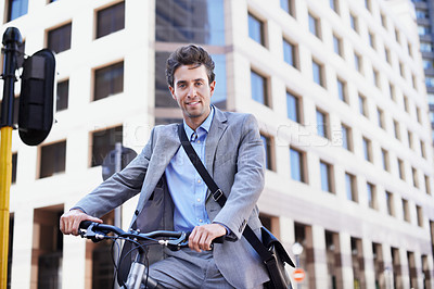 Buy stock photo A handsome businessman riding his bicycle to work in the city central