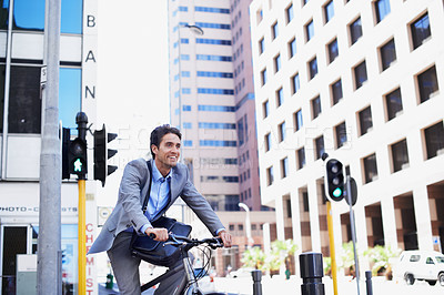 Buy stock photo A handsome businessman riding his bicycle to work in the city central