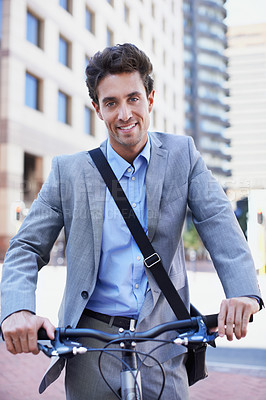 Buy stock photo A handsome businessman riding his bicycle to work in the city central