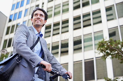 Buy stock photo A handsome businessman riding his bicycle to work in the city central