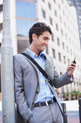 Buy stock photo A handsome businessman using his mobile in the city central
