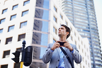 Buy stock photo A handsome businessman using his smartphone to get direction in the city central