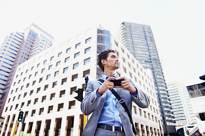 Buy stock photo A handsome businessman using his smartphone to get direction in the city central
