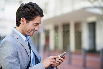 Buy stock photo An attractive businessman using his mobile while in the city central