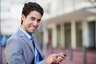 Buy stock photo An attractive businessman using his mobile while in the city central