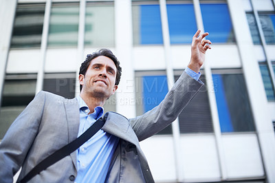 Buy stock photo A handsome businessman hailing a taxi in the city