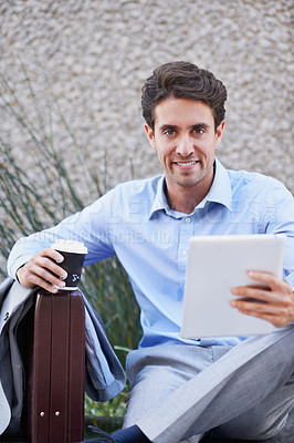 Buy stock photo A handsome businessman using his tablet while sitting out in the city central and having a break