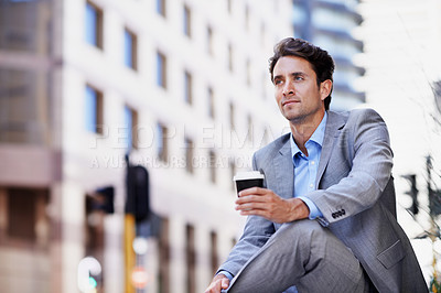 Buy stock photo A handsome businessman having a cup of coffee while relaxing in the city