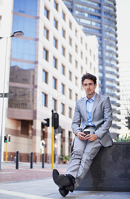 Buy stock photo A handsome businessman having a cup of coffee while relaxing in the city